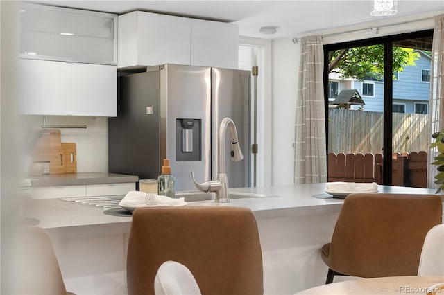9587 W 89th Cir, Broomfield, CO 80021 - kitchen featuring stainless steel fridge with ice dispenser, white cabinetry, modern cabinets, light countertops, and a kitchen breakfast bar