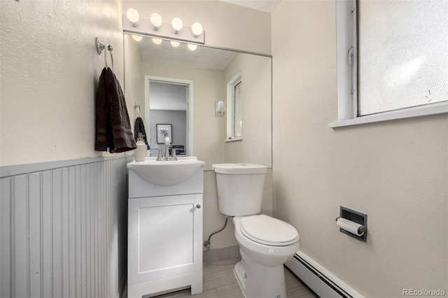 half bath with baseboard heating, vanity, and toilet