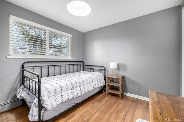 bedroom featuring baseboard heating, wood finished floors, and baseboards