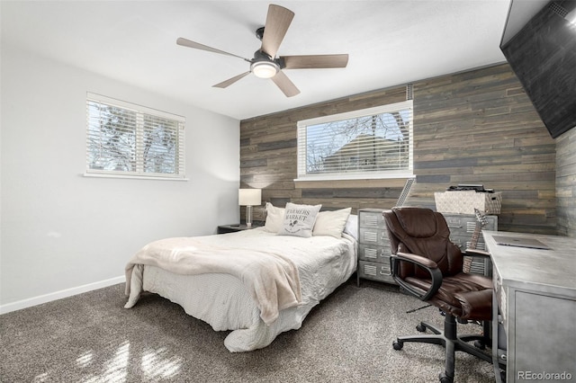 bedroom featuring an accent wall, multiple windows, wooden walls, and baseboards