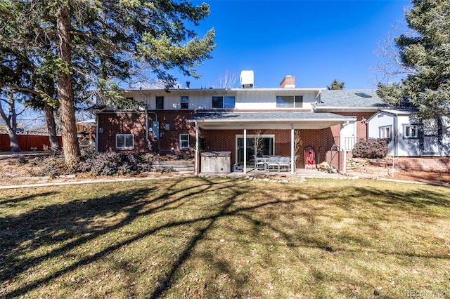 rear view of house featuring a yard, brick siding, a chimney, and a patio area