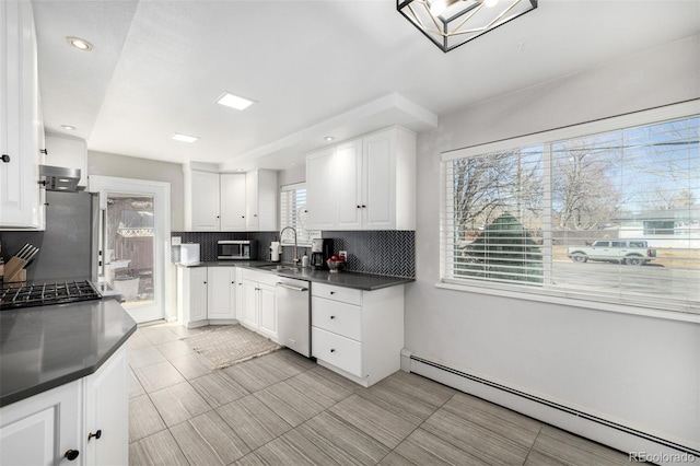 kitchen featuring backsplash, a baseboard heating unit, appliances with stainless steel finishes, white cabinetry, and a sink