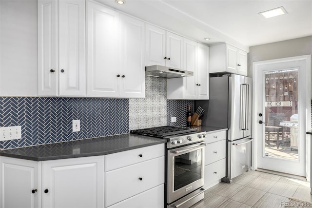 kitchen featuring appliances with stainless steel finishes, dark countertops, white cabinetry, and under cabinet range hood