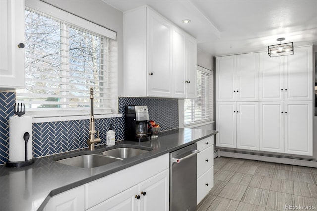 kitchen with dark countertops, a wealth of natural light, white cabinetry, and stainless steel dishwasher