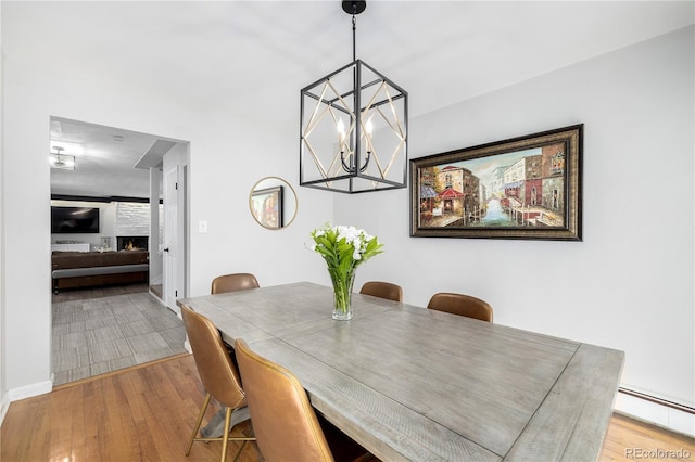 dining room with a chandelier, baseboard heating, and wood finished floors