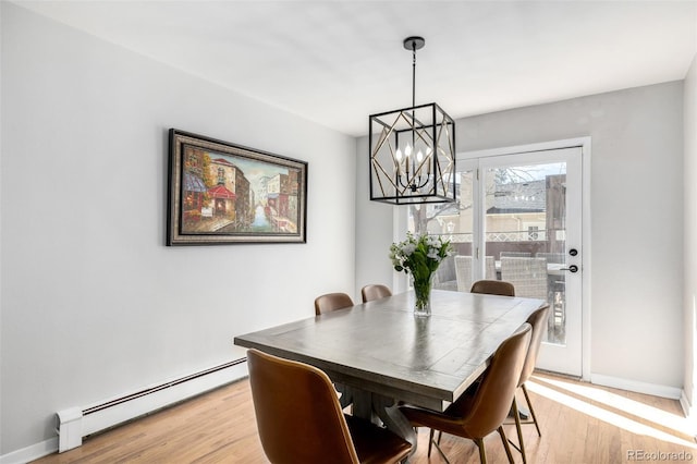 dining room featuring light wood-type flooring, a baseboard radiator, a chandelier, and baseboards