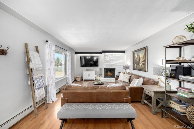 interior space with a large fireplace, baseboard heating, and light wood-style floors