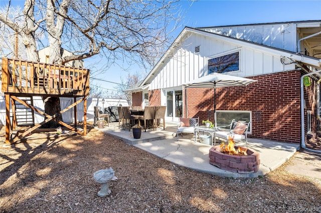 rear view of property featuring an outdoor fire pit, a patio, board and batten siding, and brick siding