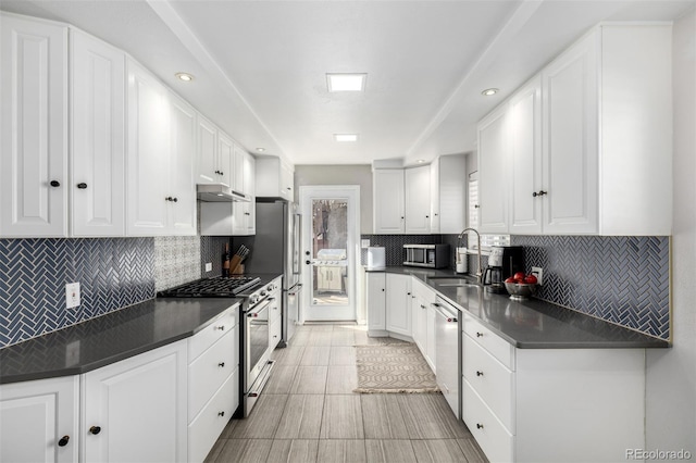 kitchen with stainless steel appliances, white cabinets, a sink, and under cabinet range hood