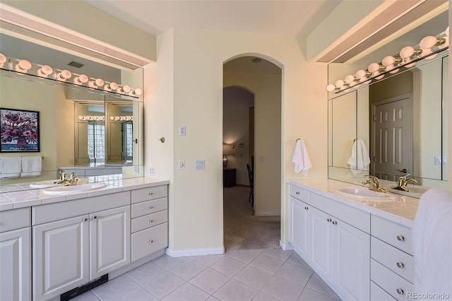 full bath featuring tile patterned flooring, two vanities, and baseboards
