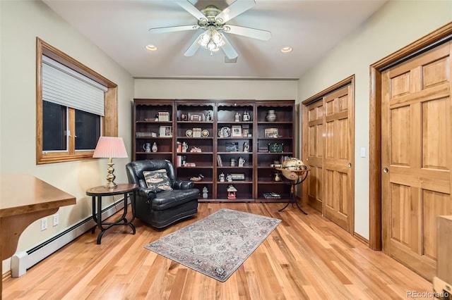 living area featuring wood finished floors, a ceiling fan, baseboard heating, and recessed lighting
