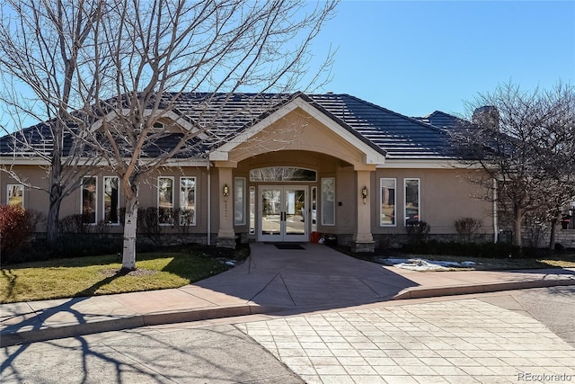 doorway to property with french doors, stucco siding, a lawn, and a chimney