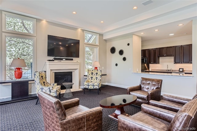 living room featuring dark colored carpet, recessed lighting, baseboards, and a glass covered fireplace