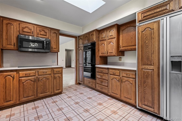 7351 Poppy Way, Arvada, CO 80007 - kitchen with black appliances, a skylight, light countertops, and brown cabinetry