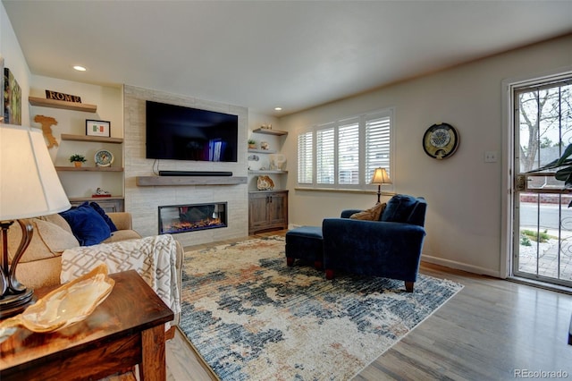 living area with built in features, wood finished floors, a fireplace, baseboards, and recessed lighting