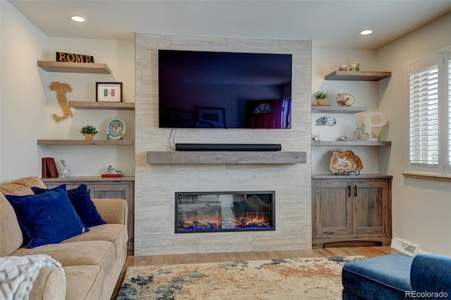 living room featuring recessed lighting, wood finished floors, and a tile fireplace