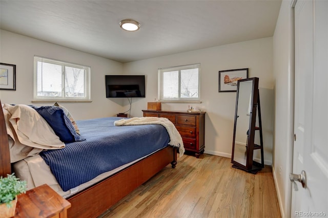 bedroom featuring baseboards, multiple windows, and light wood-style flooring