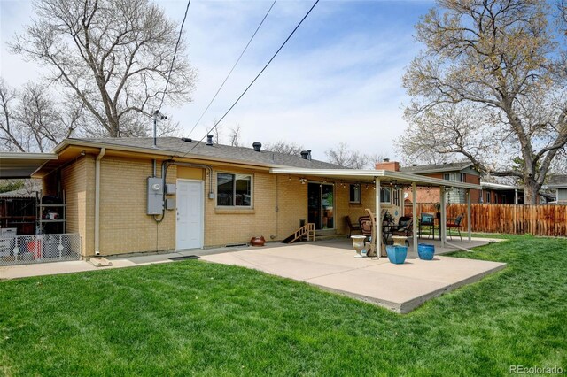 rear view of property with fence, brick siding, a chimney, a patio area, and a yard