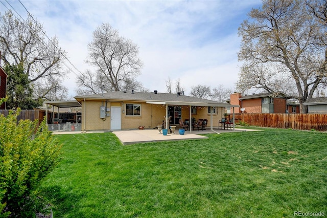 back of property with a patio, a fenced backyard, a lawn, and brick siding