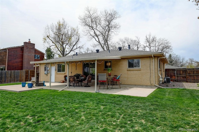 rear view of house featuring a fenced backyard, a yard, a patio area, and brick siding