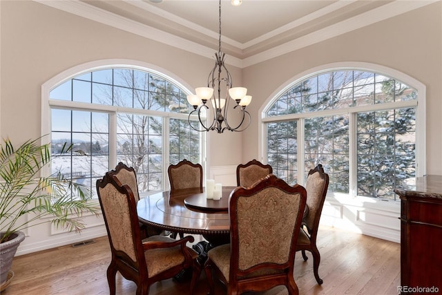 dining space with crown molding, a notable chandelier, and light wood-type flooring