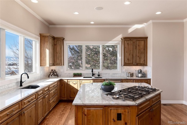 kitchen with a kitchen island, stainless steel gas cooktop, sink, and light hardwood / wood-style flooring