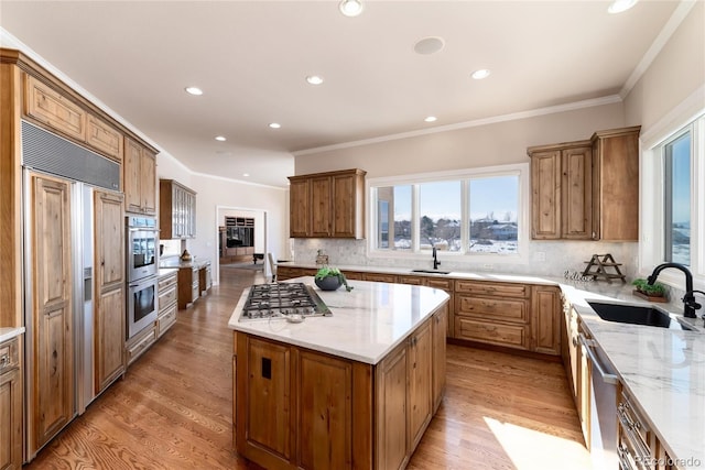 kitchen featuring stainless steel appliances, a kitchen island, sink, and light hardwood / wood-style floors