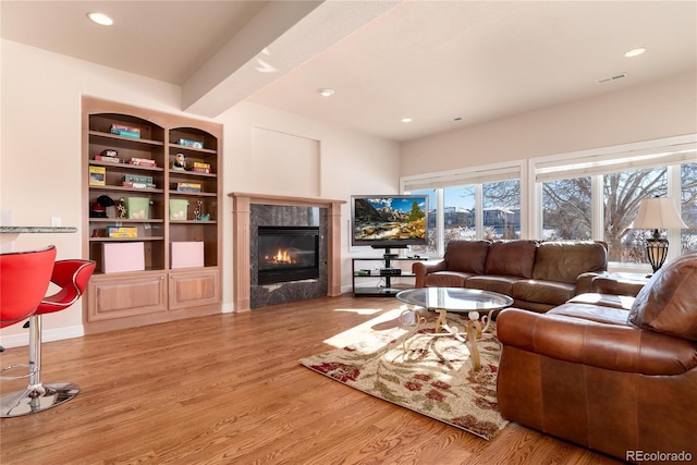 living room featuring built in shelves, a fireplace, and light wood-type flooring