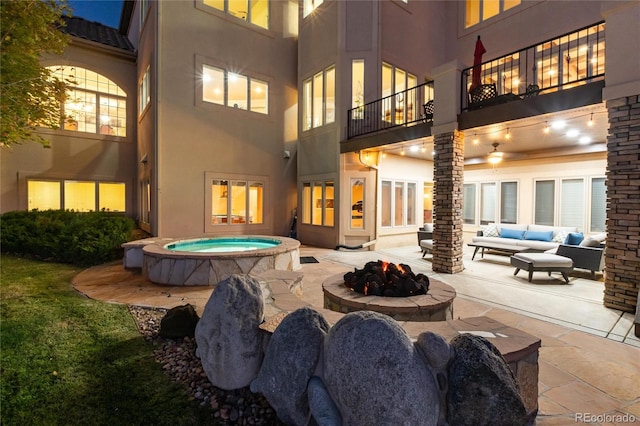 back of house featuring a patio area, an outdoor living space with a fire pit, and an in ground hot tub