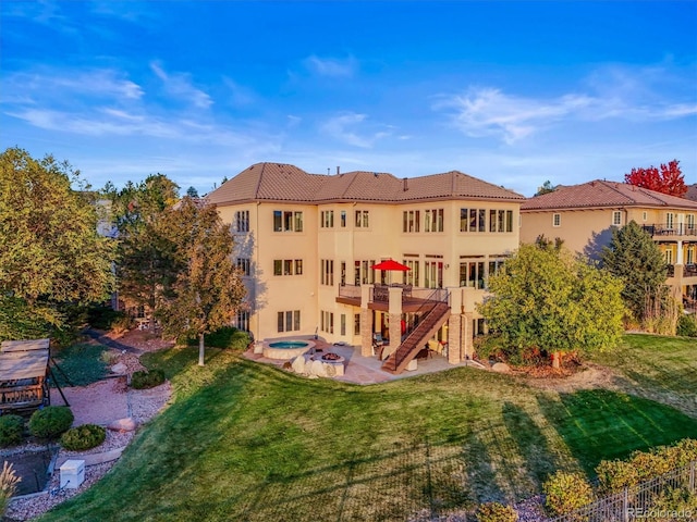 rear view of property with an in ground hot tub, a lawn, a deck, and a patio area