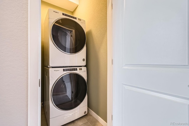 laundry area with stacked washing maching and dryer and light tile patterned flooring