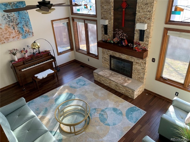 living room with wood-type flooring, a fireplace, a ceiling fan, and baseboards