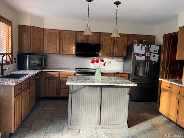 kitchen featuring light stone counters, a center island, stainless steel appliances, tasteful backsplash, and a sink