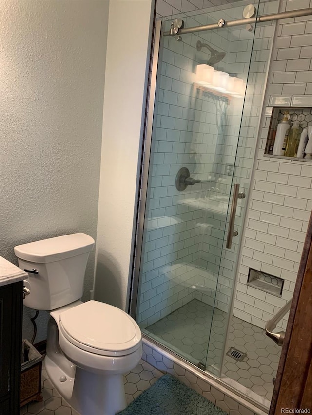 full bathroom with a textured wall, toilet, vanity, tile patterned floors, and a stall shower