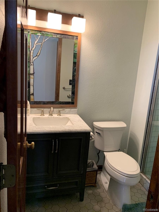 bathroom with toilet, a textured wall, tile patterned floors, and vanity