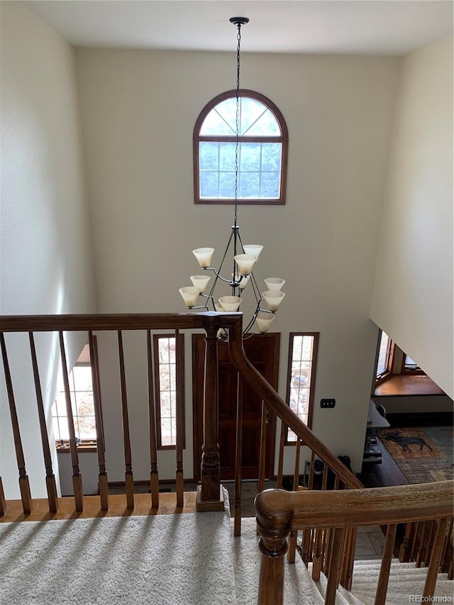 staircase featuring an inviting chandelier, plenty of natural light, and a high ceiling