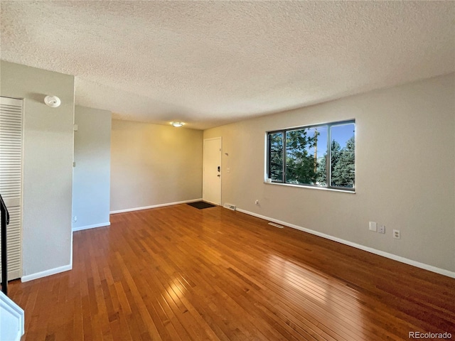 spare room featuring hardwood / wood-style floors and a textured ceiling