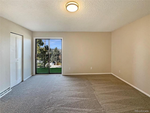 carpeted empty room featuring a textured ceiling