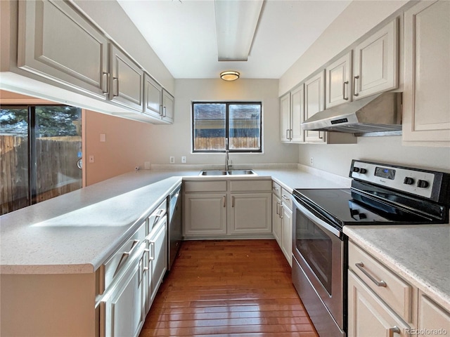 kitchen featuring dark hardwood / wood-style floors, plenty of natural light, kitchen peninsula, and appliances with stainless steel finishes