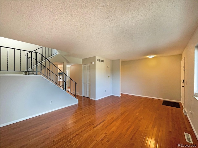 unfurnished living room with a textured ceiling and dark hardwood / wood-style flooring