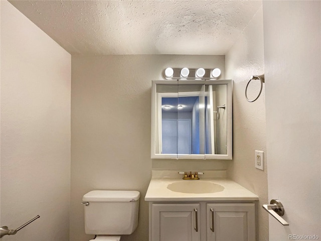 bathroom with vanity, toilet, and a textured ceiling