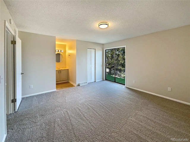 unfurnished bedroom with ensuite bath, carpet floors, a textured ceiling, access to outside, and a closet