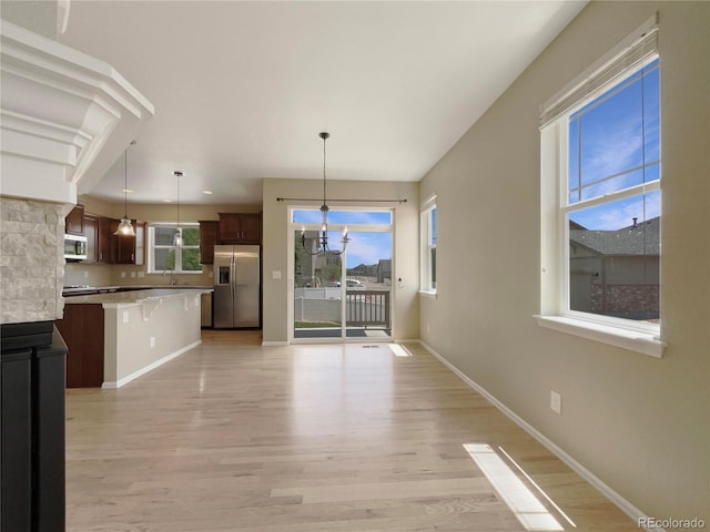 2258 Whistler Dr, Longmont, CO 80504 - kitchen with appliances with stainless steel finishes, light countertops, light wood-type flooring, baseboards, and a breakfast bar area