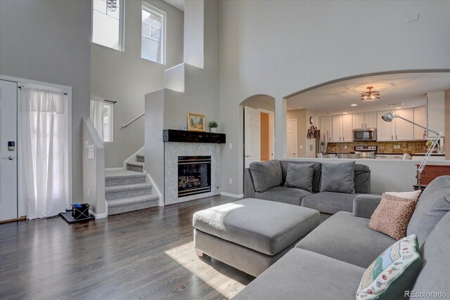 living room with a high ceiling, hardwood / wood-style flooring, and a tile fireplace