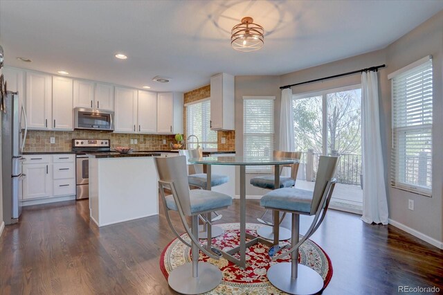 kitchen with a healthy amount of sunlight, stainless steel appliances, dark hardwood / wood-style flooring, and white cabinets