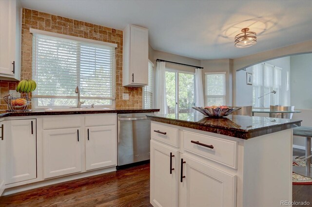 kitchen with dishwasher, dark hardwood / wood-style floors, dark stone counters, a center island, and white cabinetry