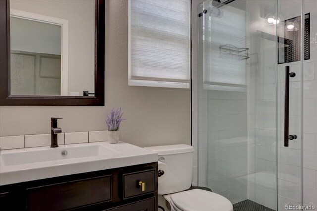 bathroom featuring a shower with door, vanity, and toilet