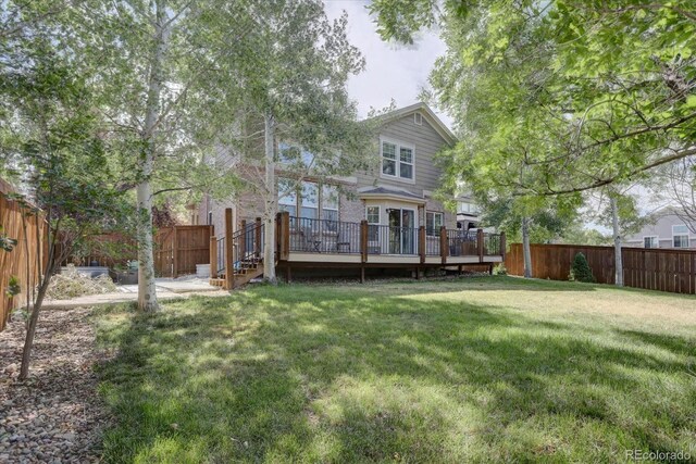 back of house featuring a wooden deck and a lawn