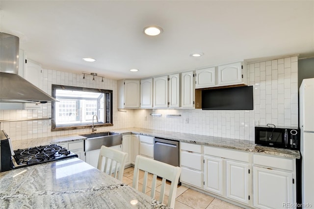 kitchen featuring light stone countertops, wall chimney range hood, white cabinets, and light tile patterned floors