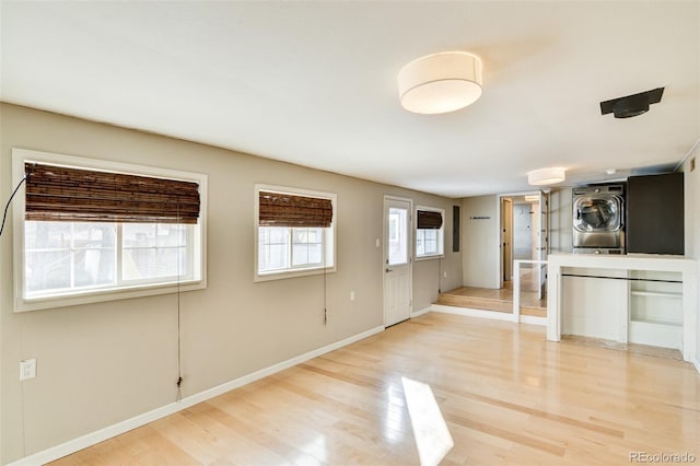 unfurnished living room with stacked washer / dryer and wood-type flooring